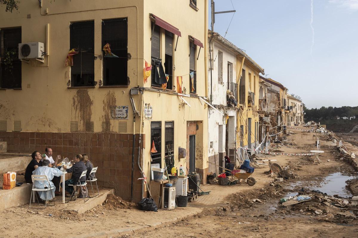 Calle Almassereta en Picanya, con la familia de la vivienda afectada comiendo en la puerta de casa.