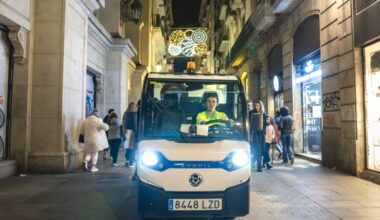 Una persona del servei de neteja condueix el seu vehicle per un carrer guarnit de Nadal