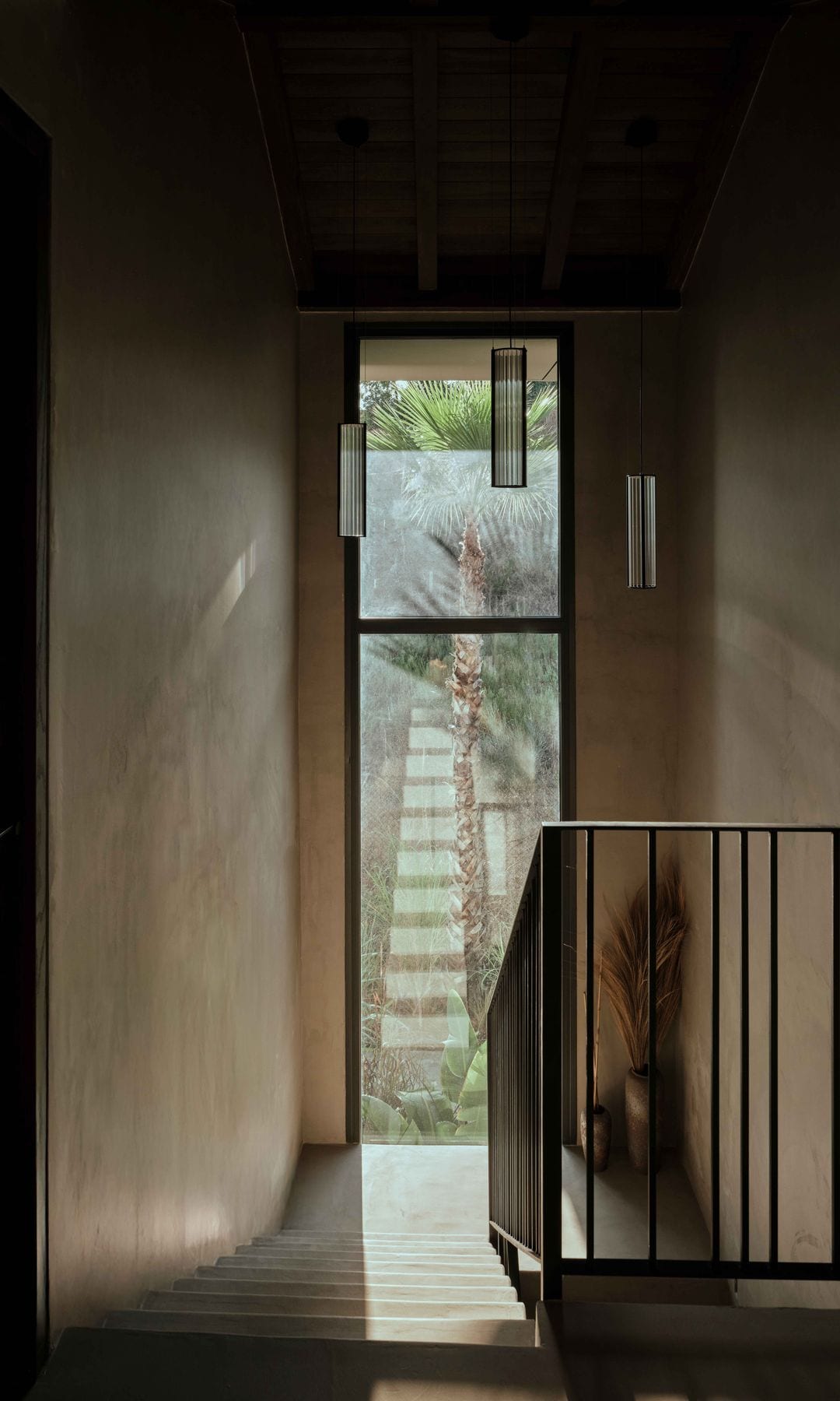 Escalera con barandilla metálica negra y ventanal en el rellano 