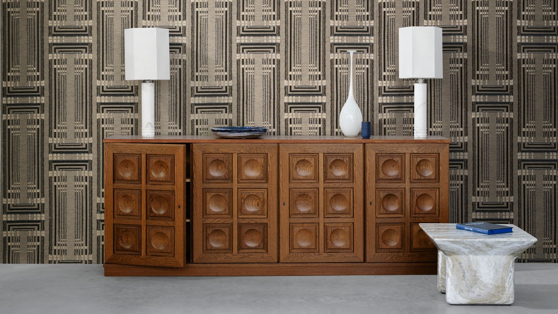 Pared con papel pintado, aparador vintage de madera, lámparas de sobremesa blancas, mesa auxiliar de mármol