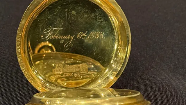 Un reloj de oro con una inscripción grabada con el 6 de febrero 1888