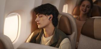 Un joven escucha música con los auriculares HUAWEI FREEBUDS 6i mientras viaja en avión