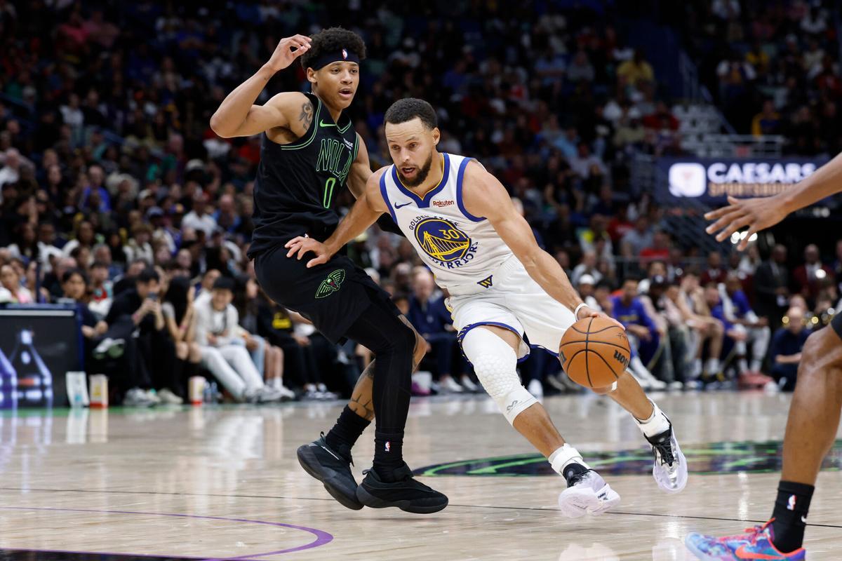 Golden State Warriors guard Stephen Curry (30) dribbles around New Orleans Pelicans guard Jeremiah Fears (0) during the second quarter of an NBA basketball game, Sunday, Nov. 16, 2025, in New Orleans. (AP Photo/Butch Dill)