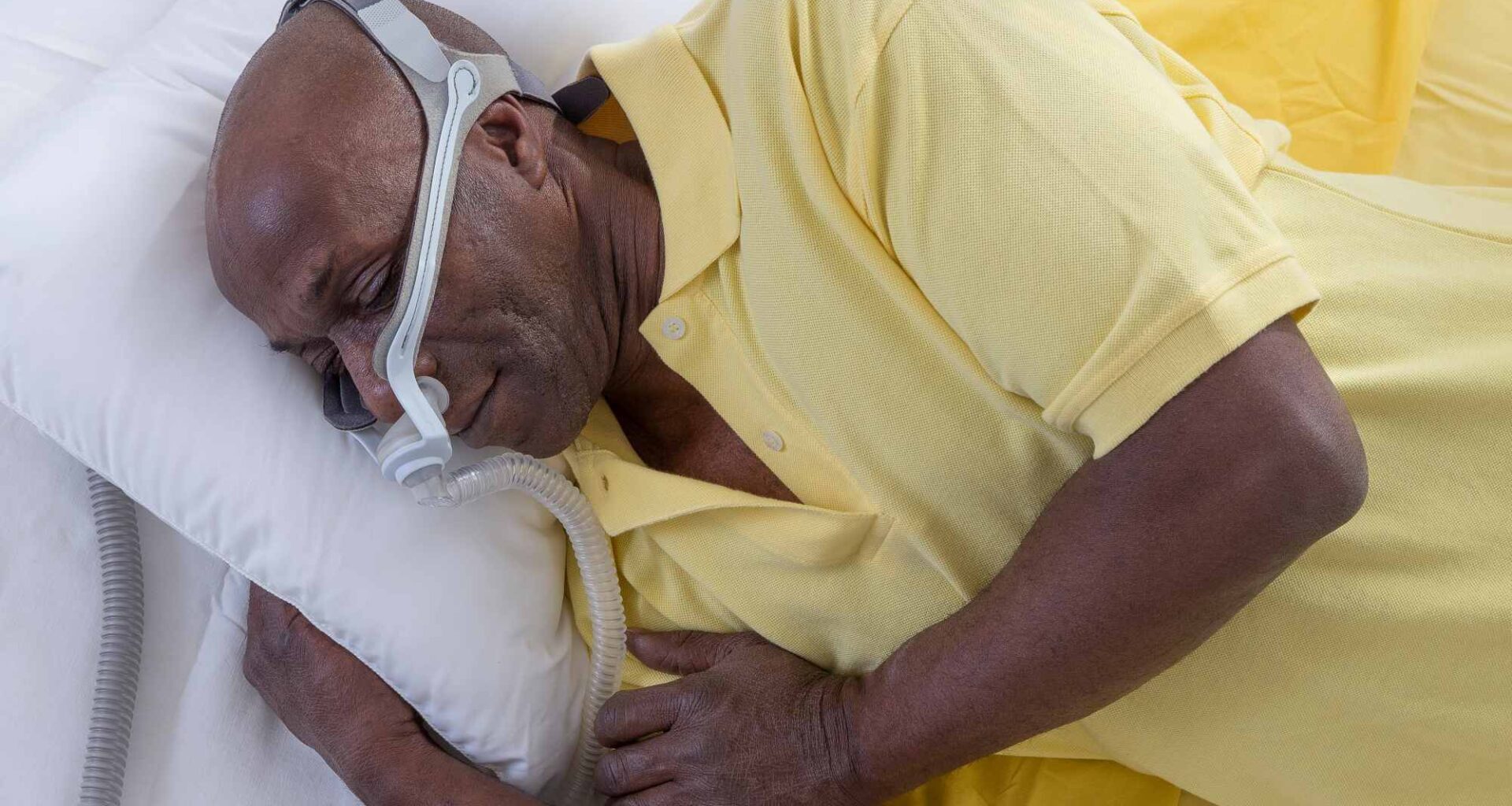 Hombre con máscara para tratamiento de la apnea del sueño. Adobe Stock