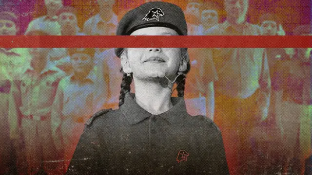 Una colegiala con uniforme militar mira hacia arriba; sus ojos están cubiertos por una tira que atraviesa toda la fotografía.