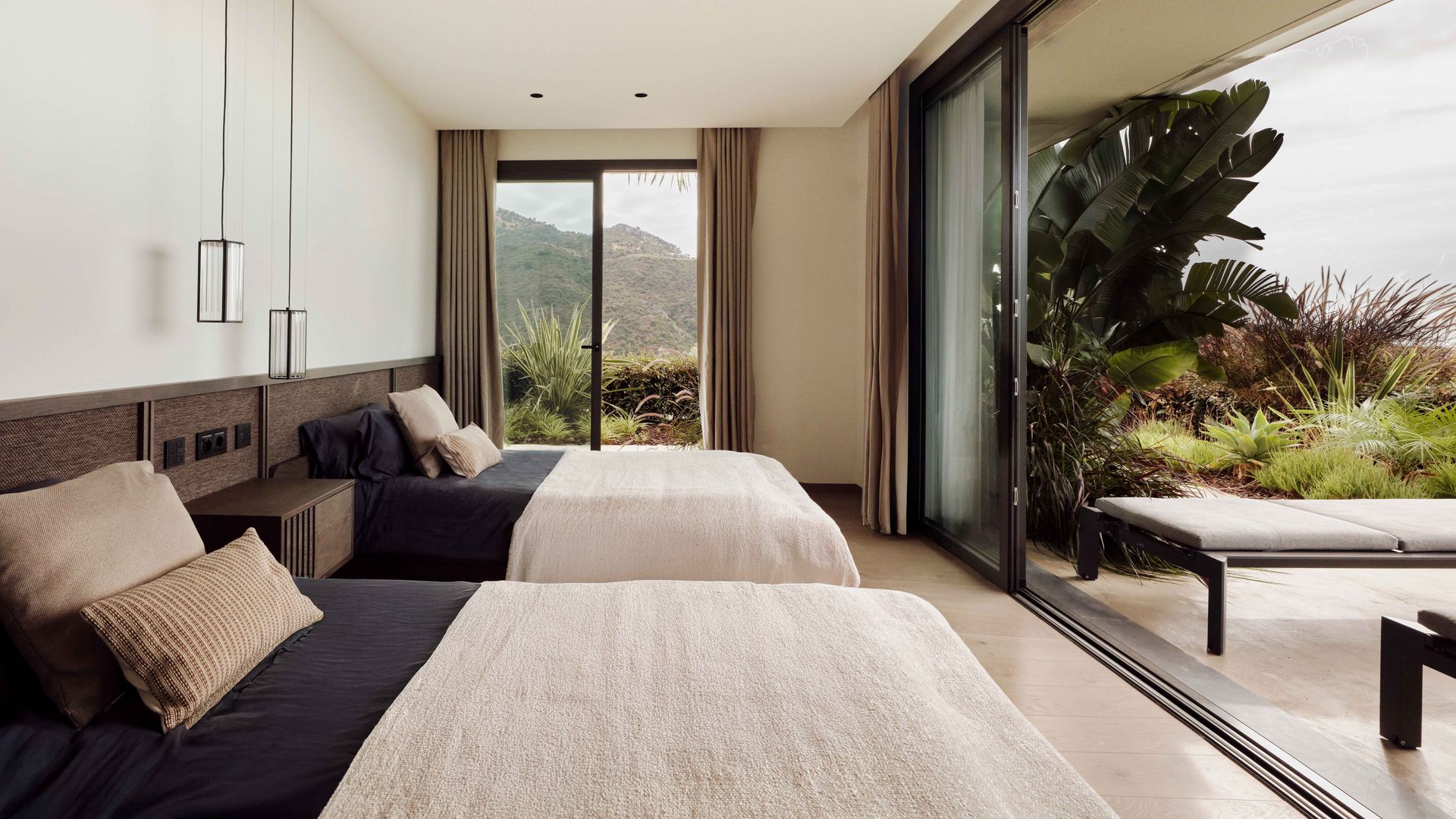 Dormitorio con dos camas, corredera de cristal con salida a la terraza, lámparas de techo, cortinas beiges
