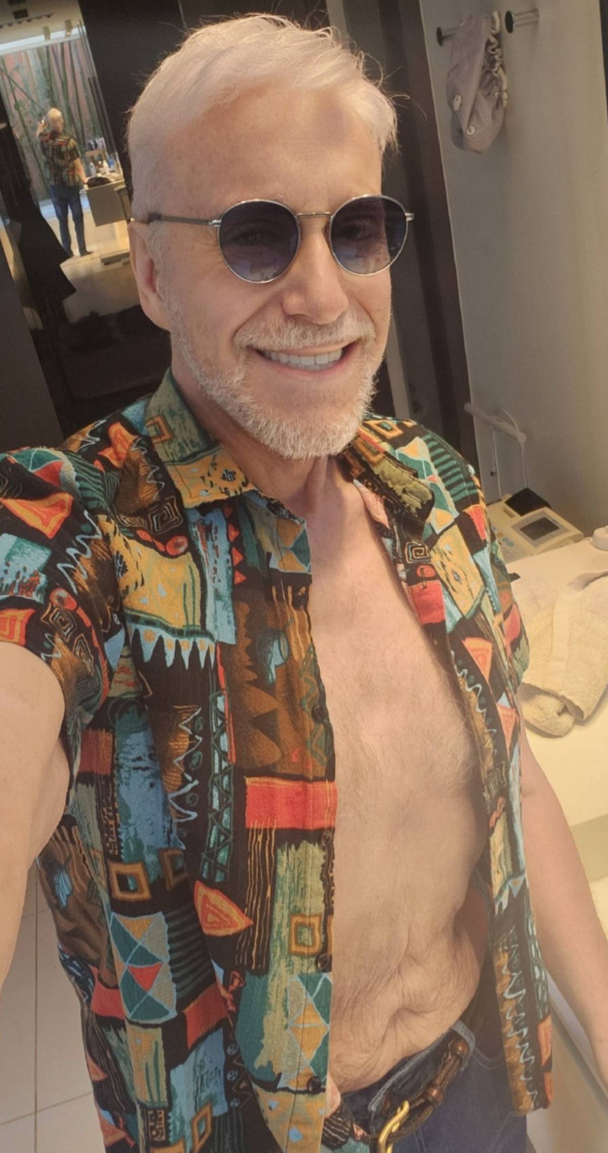Mainat haciéndose un selfi en el baño, con camisa estampada abierta y gafas de sol. (Foto: Redes Sociales)