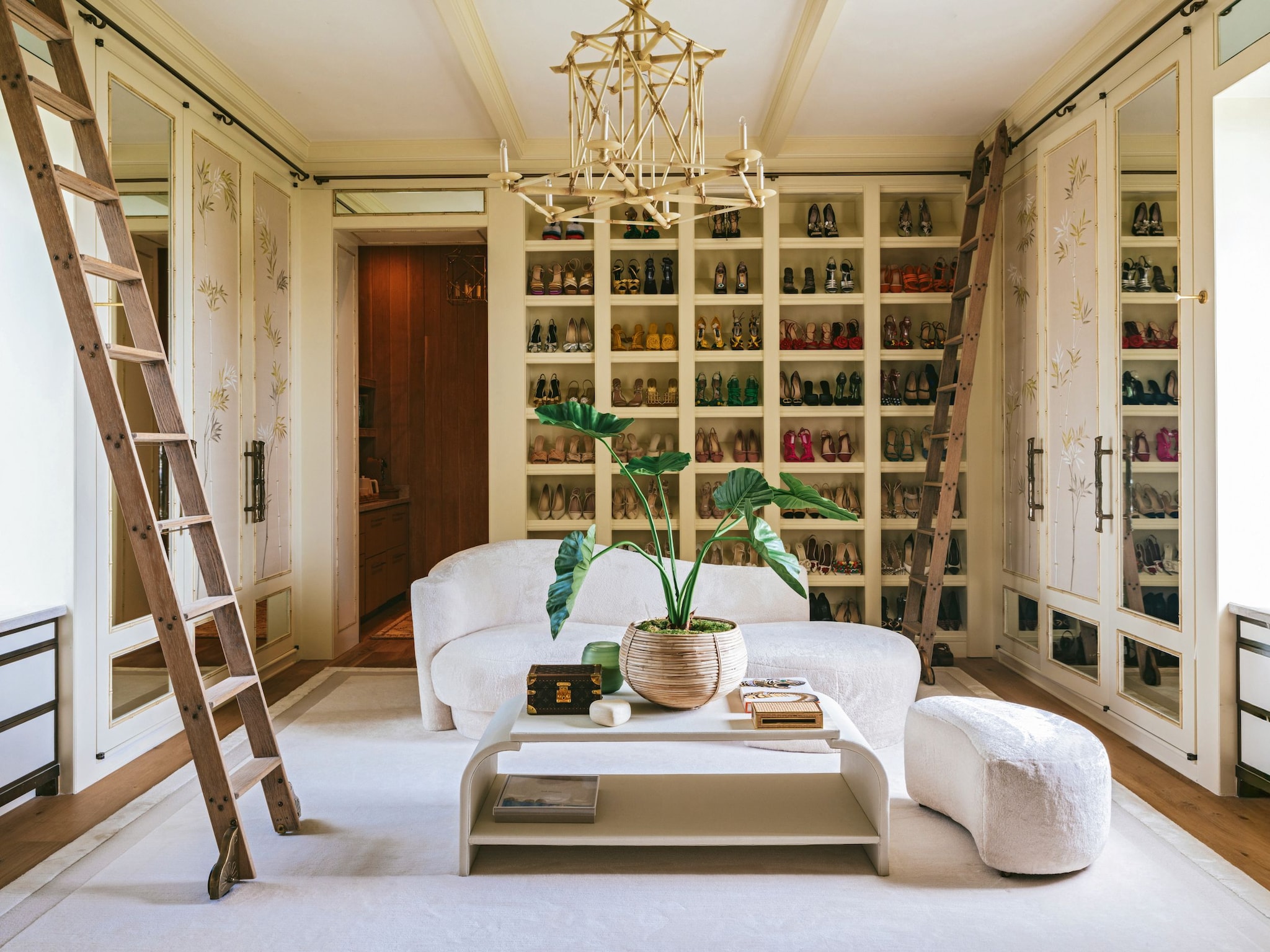 Vestidor con estanterías de zapatos y sofá blanco, mesa, planta decorativa y escalera 