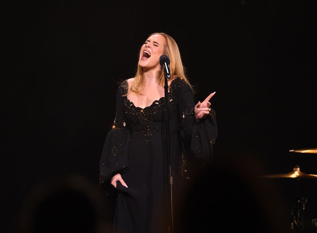 Adele en su espectáculo con vestido negro con pedrería y mangas abullonadas