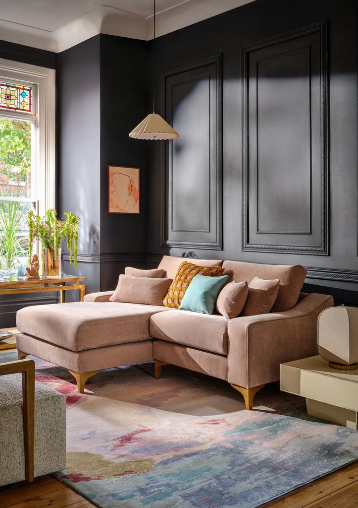 Sofá rosa palo apoyado en pared oscura