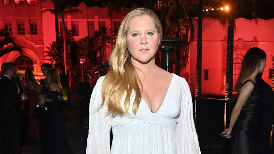 Amy Schumer posa en la alfombra roja con un vestido blanco en la 2022 Vanity Fair Oscar Party.