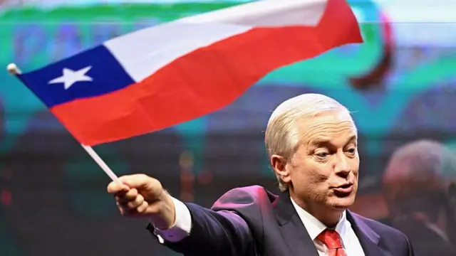 Kast ondea una bandera chilena luego de conocer los resultados de la primera vuelta de las presidenciales del domingo.