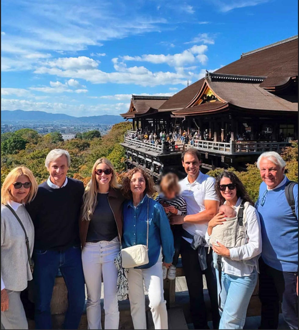 group of people posing in front of a traditional wooden structure with multiple stories group of people posing in front of a traditional wooden structure with multiple stories
