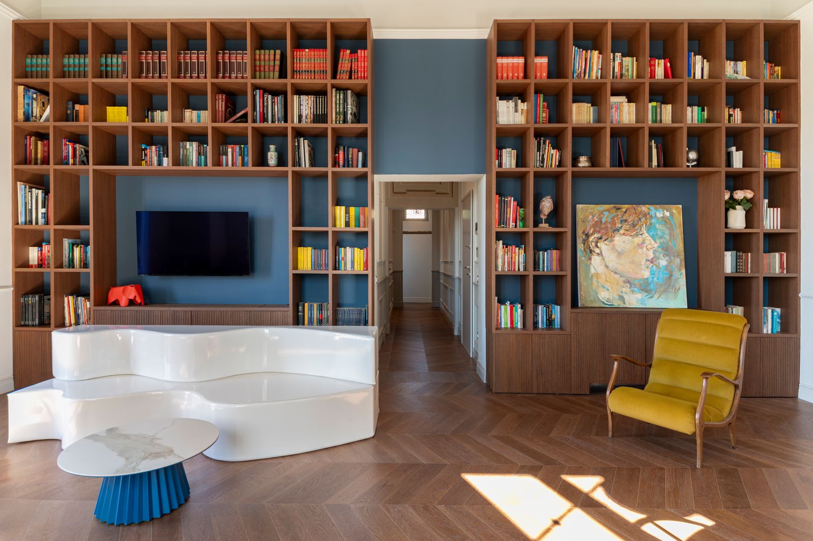 Salón azul con gran librería y sof blanco