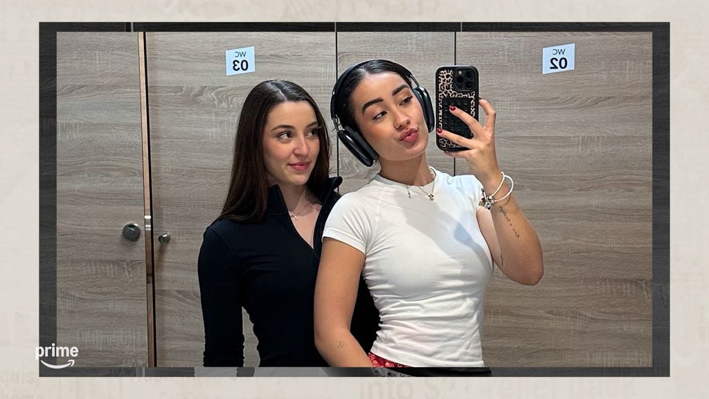 Dos mujeres en un vestuario, una con audífonos y sosteniendo un teléfono.