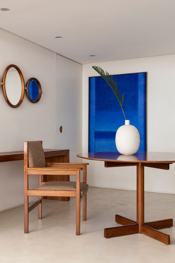 Rincón de comedor con mesa redonda y cuadro azul en la pared