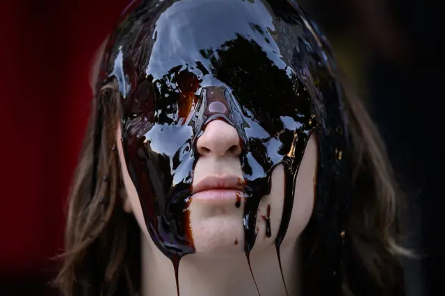 Un mujer con el rostro cubierto de una sustancia pegajosa. 