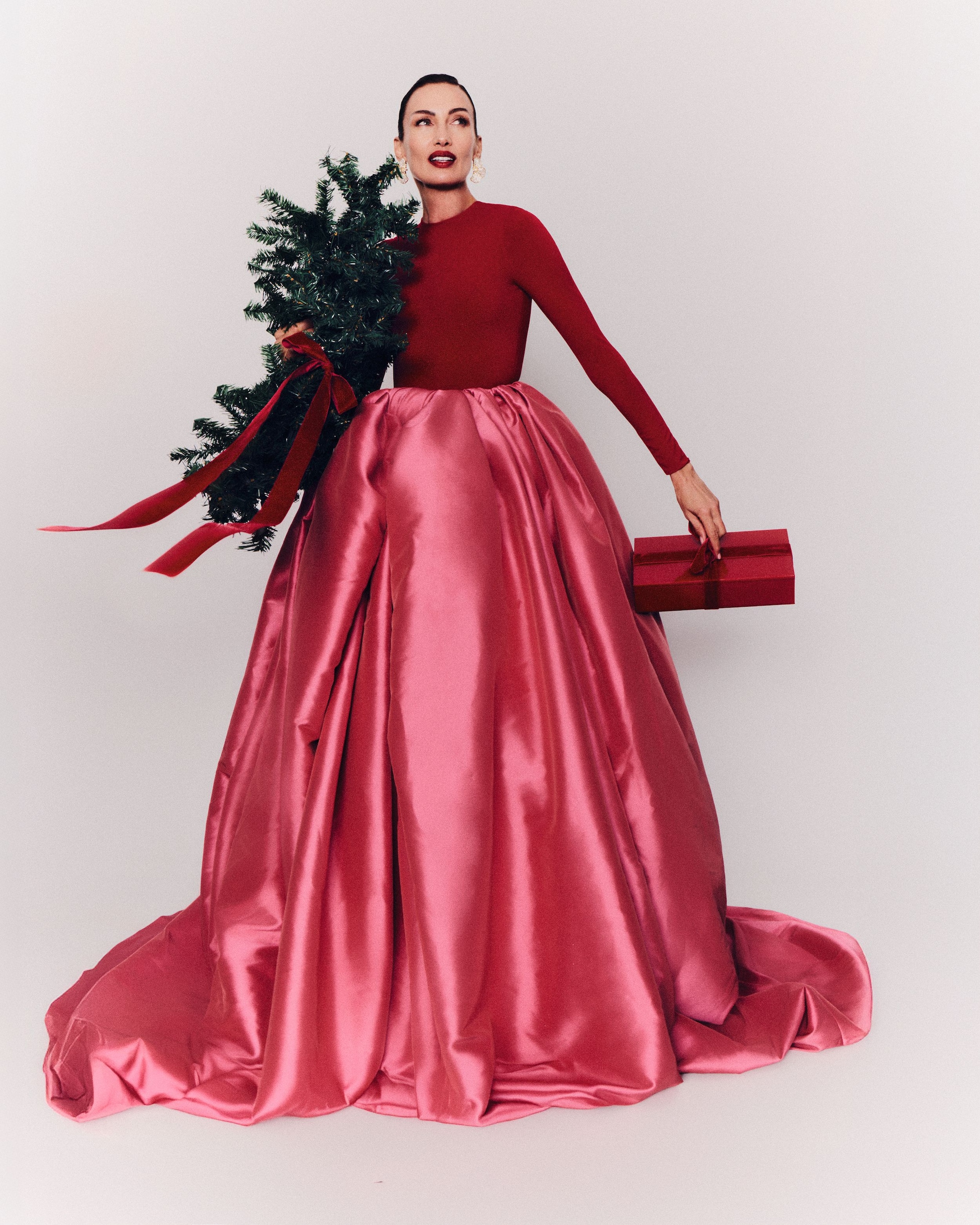 Nieves Álvarez con vestido rojo y rosa satinado, sosteniendo una piñata y una caja de regalo.