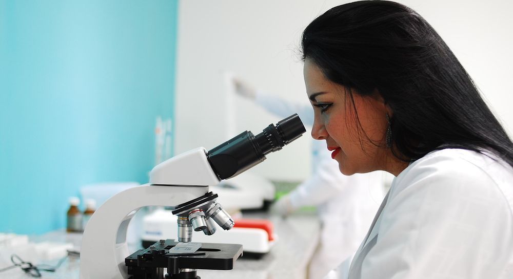 Investigadora en un laboratorio de alta seguridad analizando muestras de sangre para la cuantificación de la carga viral del VIH