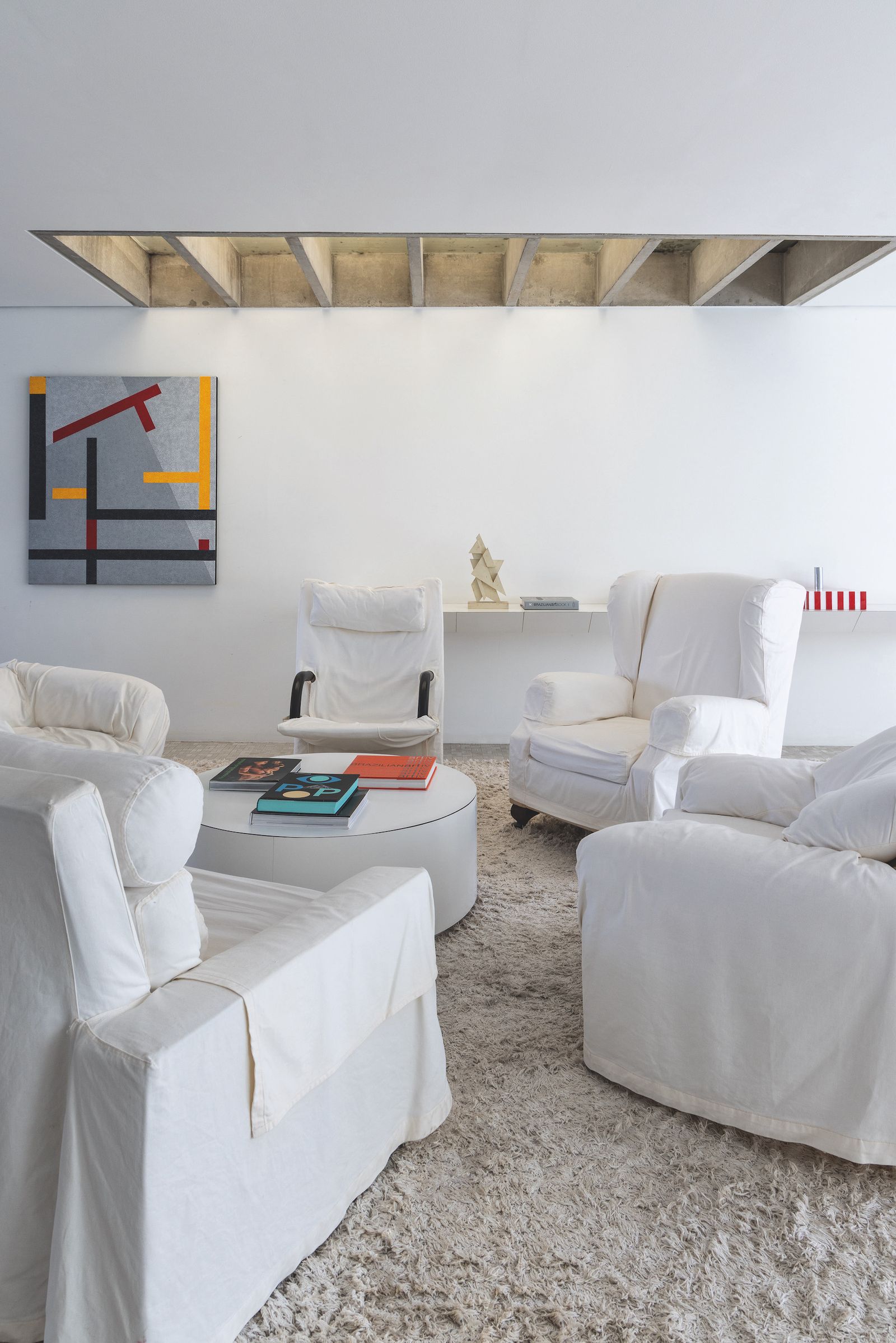 Salón blanco con sillones blancos y obras coloridas