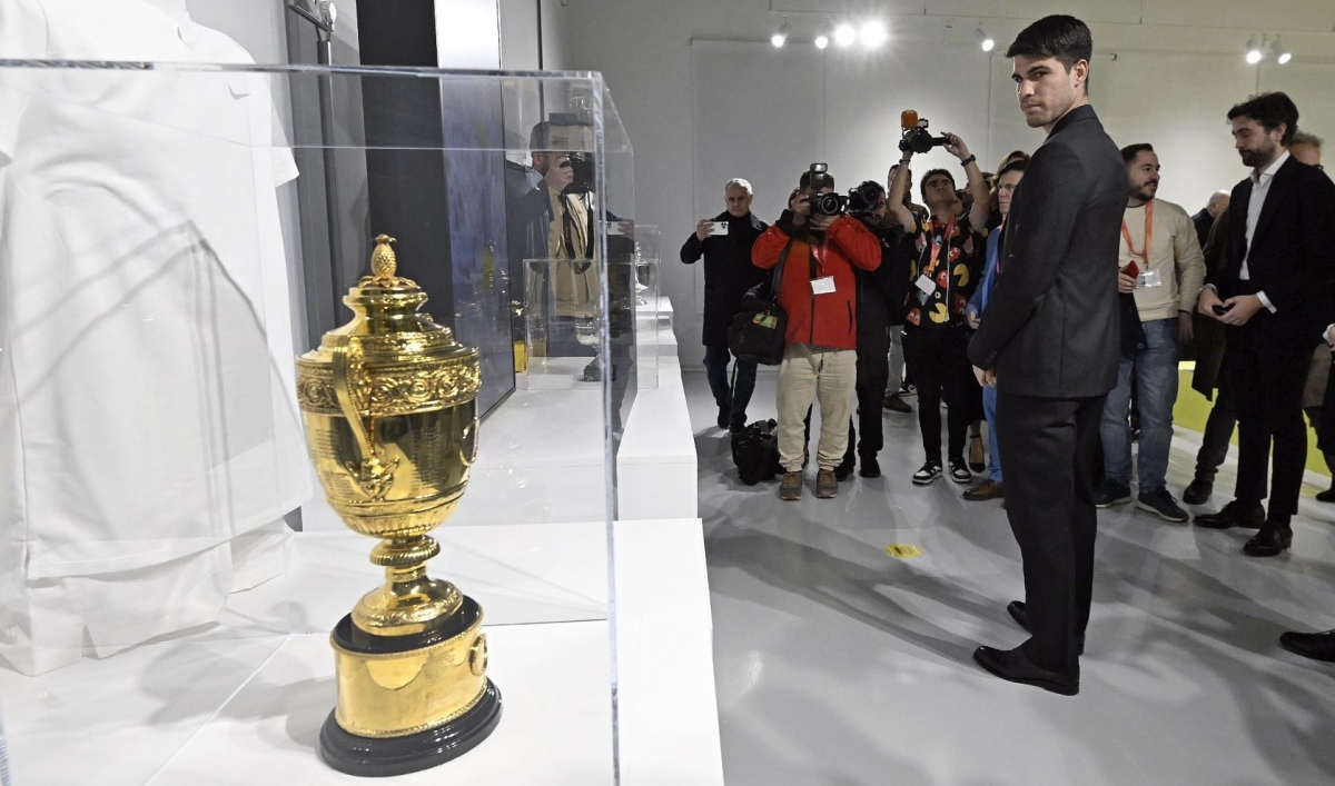 Carlos Alcaraz viendo uno de sus trofeos de Wimbledon que se mostraron en la exposición. - Foto: MP