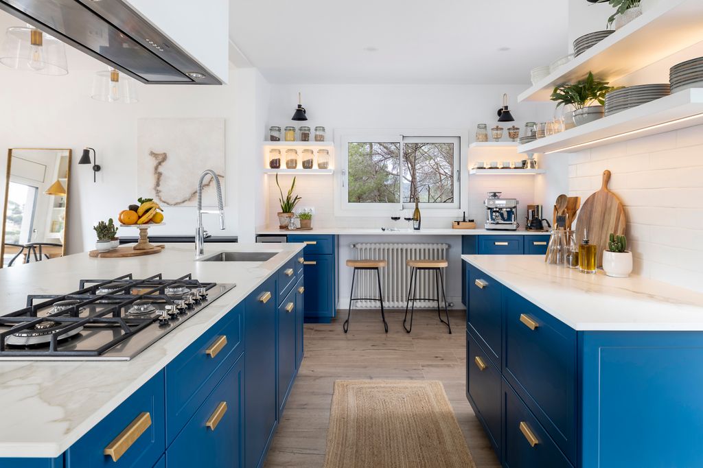 Azul vibrante, tiradores metálicos dorados y encimeras marmoleadas en una cocina en el Maresme concebida por la interiorista Montse Morales