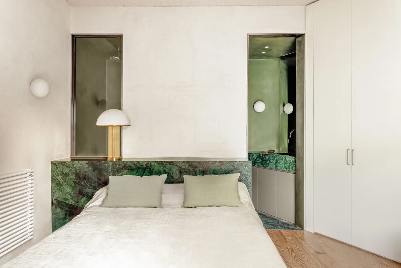 Dormitorio con baño en suite y cabecero arrimadero de mármol verde