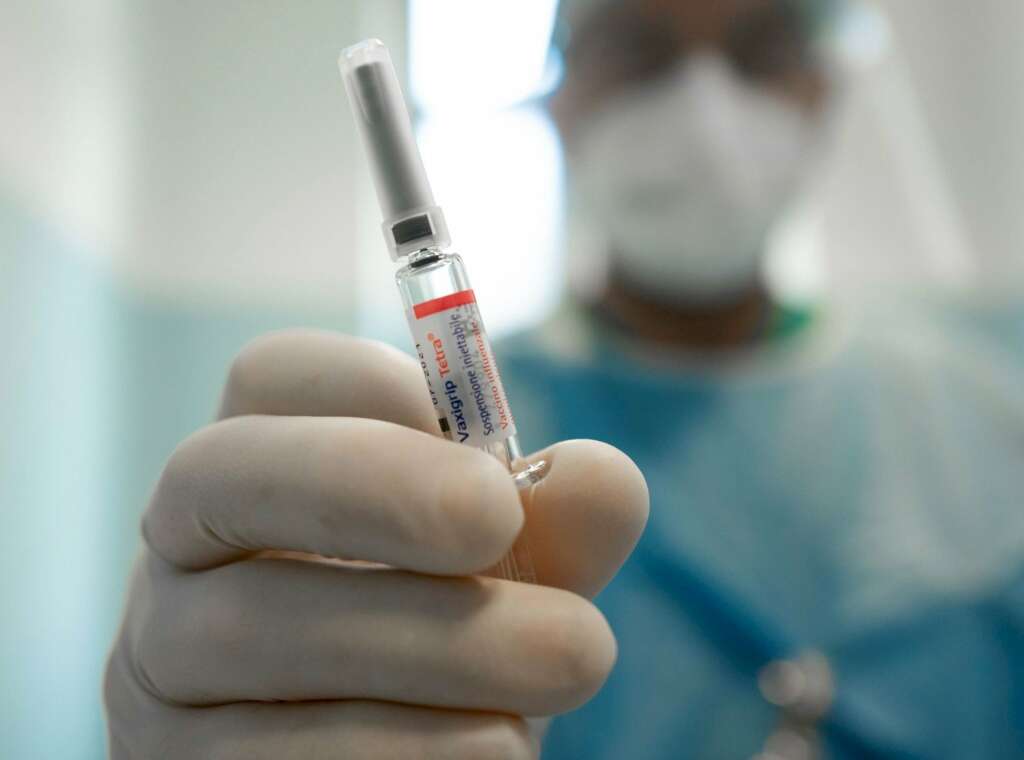 Un médico en Milán (Italia) sostiene una vacuna para la gripe / EFE