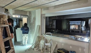 Uns treballadors fan obres de millora a la cuina de l'Escola Aldana a l'Eixample.