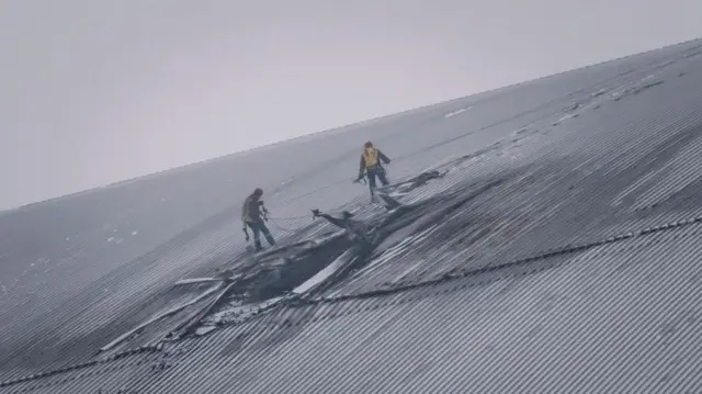 Gente inspeccionando los daños en el escudo de contención de radiación del reactor 4 de la central nuclear de Chernóbil tras un ataque con drones.