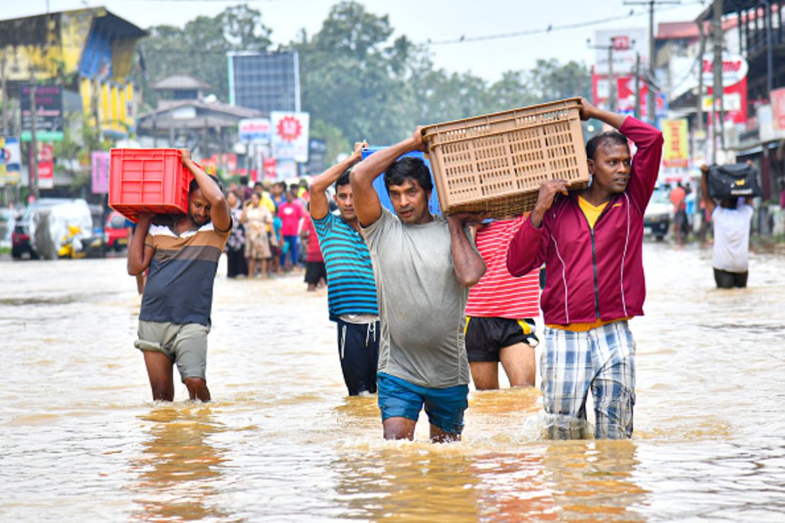 Un grupo de personas camina entre las aguas para entregar paquetes de alimentos a refugios tras las fuertes lluvias provocadas por el ciclón Ditwah en Colombo, Sri Lanka, el 29 de noviembre de 2025.