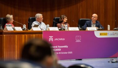 Cuatro personas sentadas en una mesa principal en una reunión