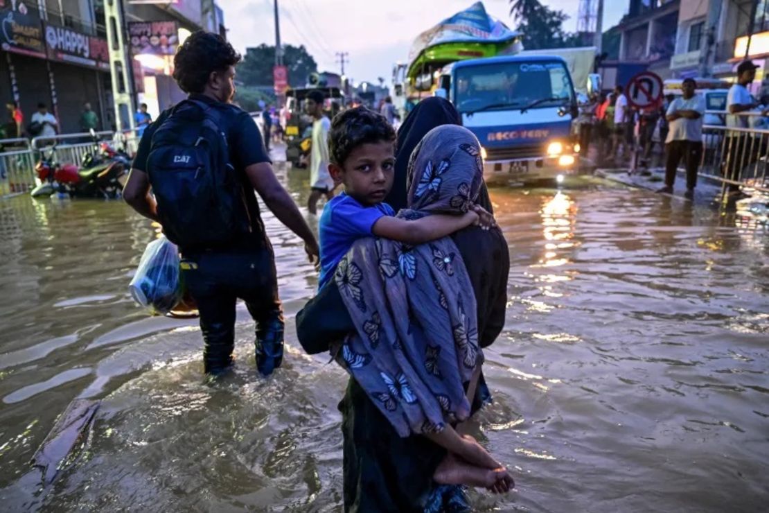 Una mujer que lleva a un niño camina por una calle inundada en Wellampitiya, en las afueras de Colombo.