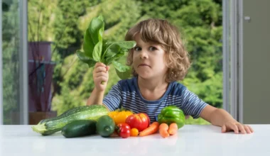 un niño con diferentes alimentos vegetales sobre una mesa