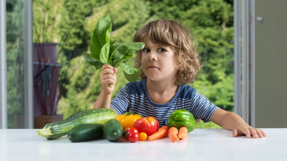 un niño con diferentes alimentos vegetales sobre una mesa