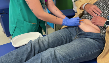 Enfermera pinchando un tratamiento a una paciente sentada