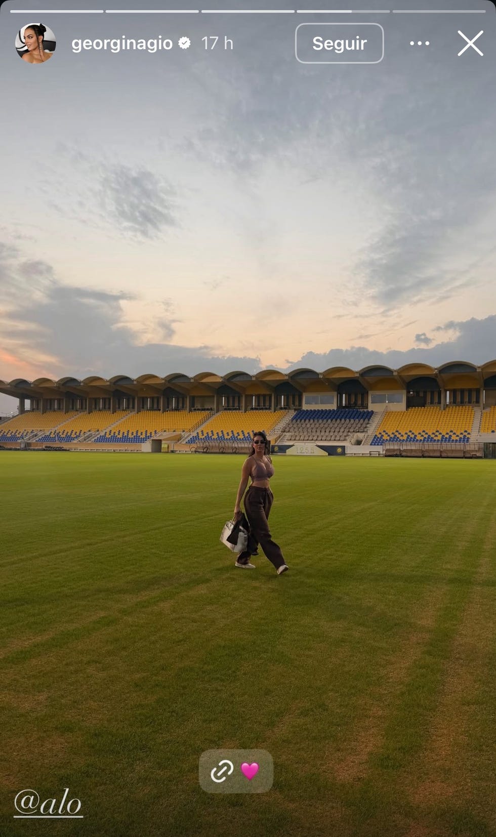 person walking on a green football field with grandstand in the background