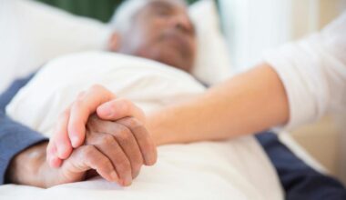 Imagen de una persona encamada con la mano enlazada con otra persona