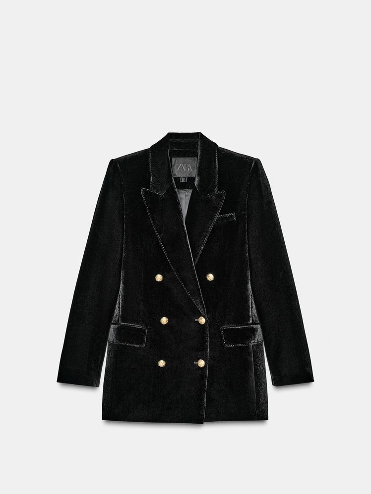 Americana de terciopelo negra cruzada con seis botones en dorado. Tiene cuello con solapa de muescas y manga larga con abertura y botones. Lleva bolsillos con solapa en delantero y de vivo en pecho.