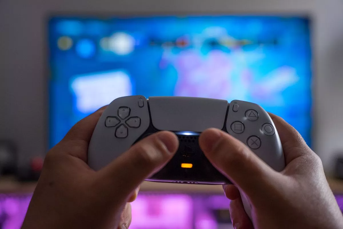  Un hombre sostiene un control DualSense frente a una pantalla de televisión