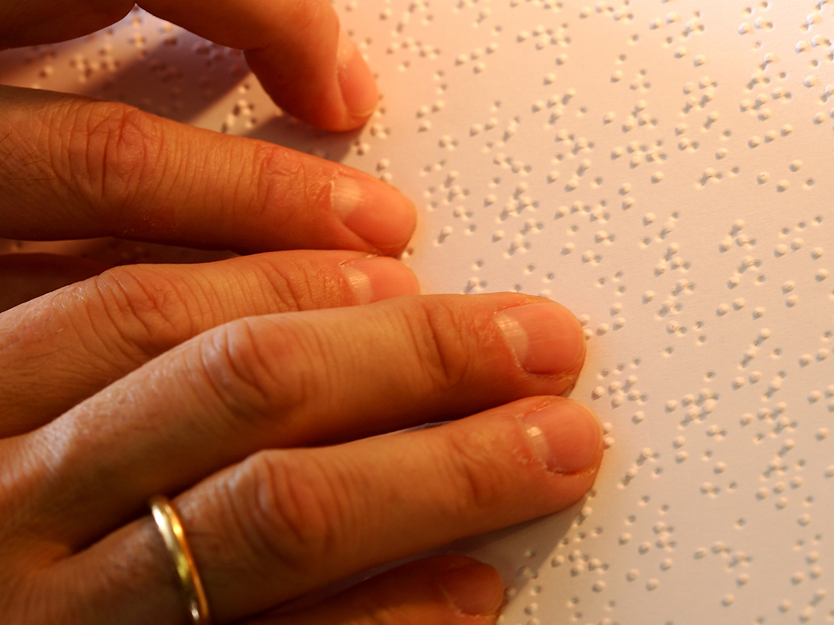Detalle de unas manos leyendo braille