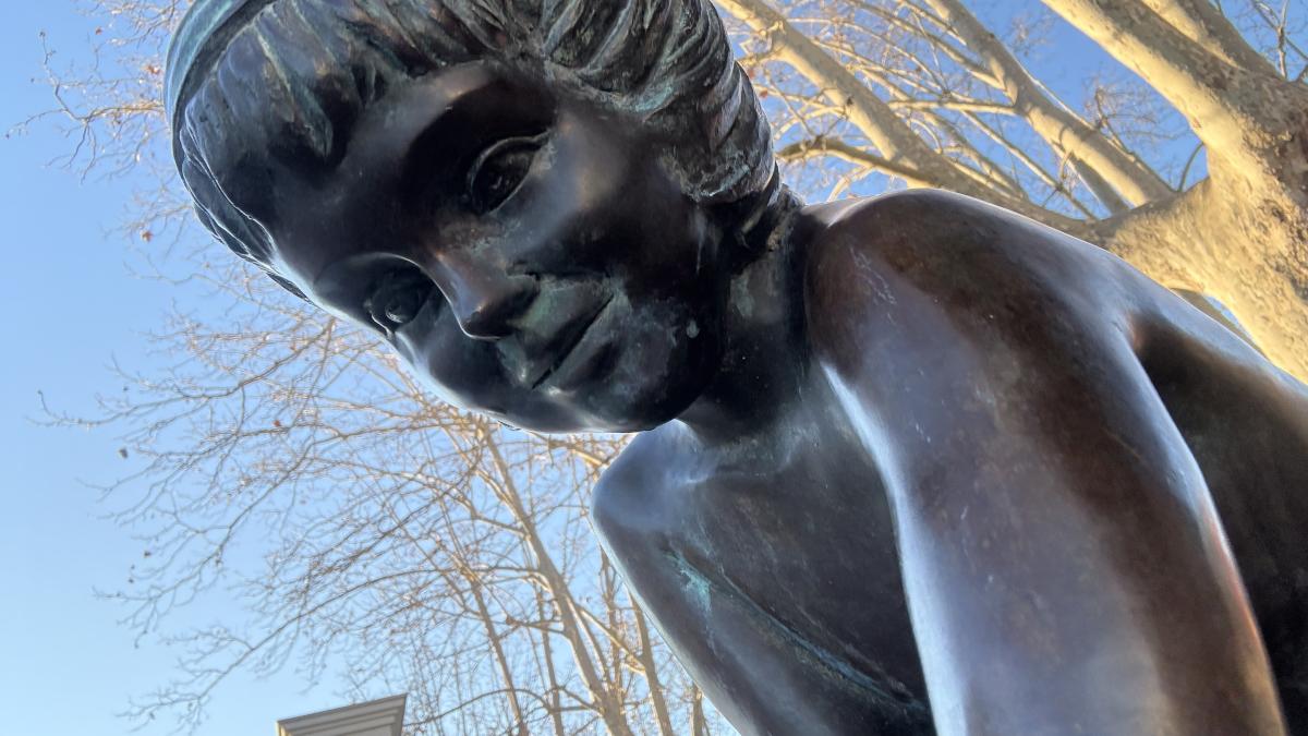 La bella escultura de la niña tocando el agua en el estanque de Banyoles