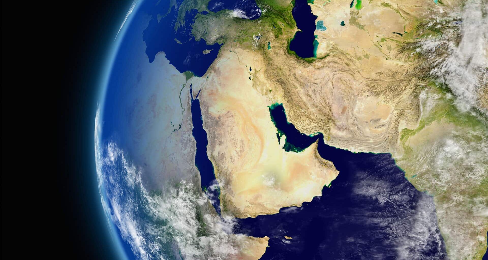 Vista satelital del globo terráqueo centrada en Oriente Medio, con regiones vecinas visibles parcialmente y algunas nubes dispersas sobre la superficie. A la izquierda, la vista se enmarca por el entorno espacial.