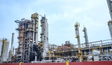 Planta de refinería de petróleo El Palito en Puerto Cabello (Estado Carabobo, Venezuela). En la imagen, múltiples torres de destilación de petróleo, hornos y una gran cantidad de sistemas de tuberías interconectados para su procesamiento. Al fondo, el cielo claro con algunas nubes.