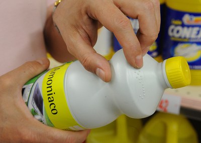 Una mano leyendo el braille de una botella de amoniaco