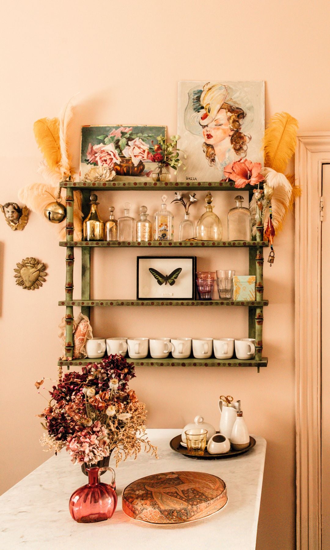 La estantería muestra preciadas botellas de vidrio, cuadros y plumas de avestruz