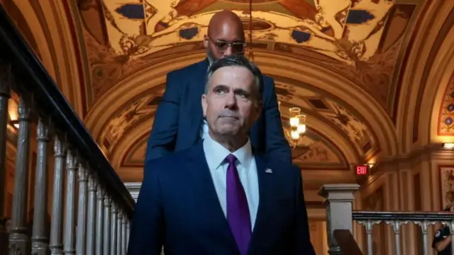 El director de la CIA, John Ratcliffe, con un hombre caminando detrás de él