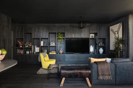 Sobre el fondo oscuro destacan las obras de arte y el sillón amarillo