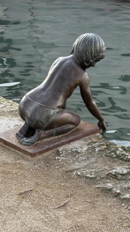 La bella escultura de la niña tocando el agua en el estanque de Banyoles.
