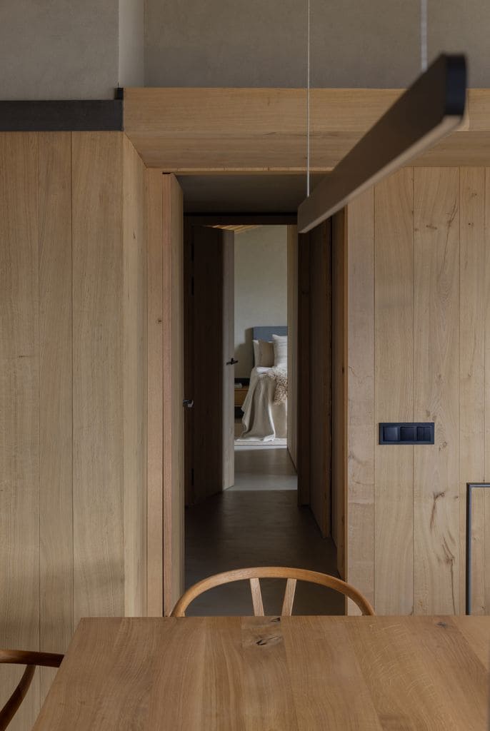 Relación del comedor con el dormitorio principal y el pasillo de madera como zona de paso